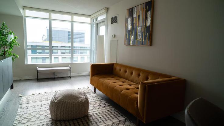 Sala de estar elegantemente projetada com móveis modernos em um apartamento no Building Dan Leckie Way - aj-properties - 1473068 em Old Toronto, Toronto
