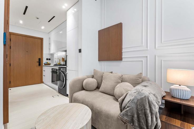 Sala de estar elegantemente projetada com móveis modernos em um apartamento no Building Mu'allaqat Boulevard - daper-holiday-homes-llc - 1397105 em Jumeirah Village, Dubai