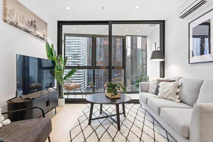 Sala de estar elegantemente projetada com móveis modernos em um apartamento no Building A'Beckett Street - eureka-stays - 1465396 em Melbourne, Melbourne Sala de estar elegantemente projetada com móveis modernos em um apartamento no Building A'Beckett Street - eureka-stays - 1465396 em Melbourne, Melbourne