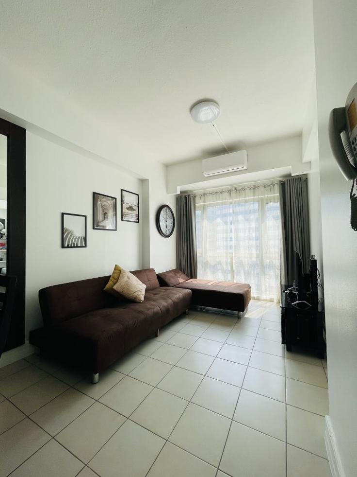 Sala de estar elegantemente projetada com móveis modernos em um apartamento no Building Rizal Drive - hosteeva - 1570758 em Makati City, Makati City