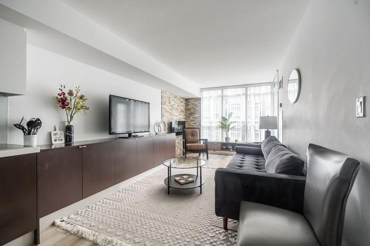 Sala de estar elegantemente projetada com móveis modernos em um apartamento no Building Dan Leckie Way - maxima-properties - 1403795 em Old Toronto, Toronto