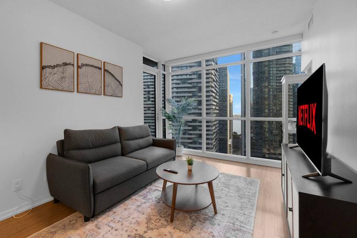 Sala de estar elegantemente projetada com móveis modernos em um apartamento no Building Bremner Boulevard - maxima-properties - 1403806 em Old Toronto, Toronto