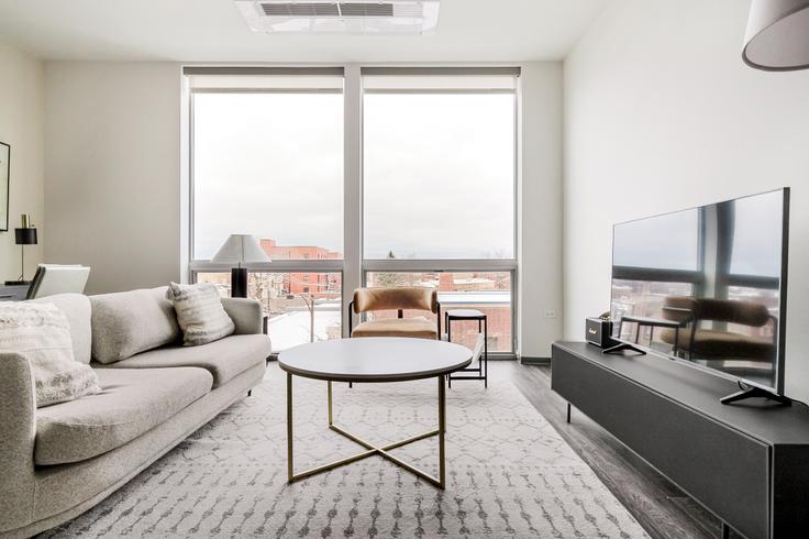 Sala de estar elegantemente projetada com móveis modernos em um apartamento no Noca Blu em Chicago, Chicago Sala de estar elegantemente projetada com móveis modernos em um apartamento no Noca Blu em Chicago, Chicago