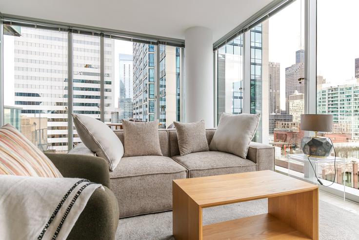 Sala de estar elegantemente projetada com móveis modernos em um apartamento no Mila em Chicago, Chicago Sala de estar elegantemente projetada com móveis modernos em um apartamento no Mila em Chicago, Chicago