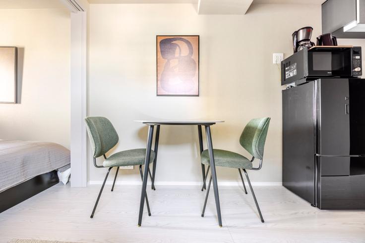 Mesa de comedor con elegantes sillas en un apartamento en Prime Garden Omori en Ota City, Tokyo