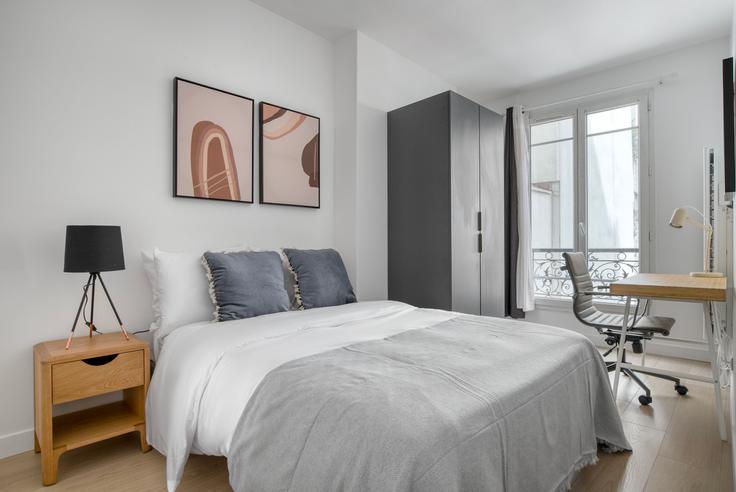 Cozy master bedroom with a large bed, soft lighting, and stylish furniture in a furnished apartment at Delta 12 in 9th arrondissement, Paris