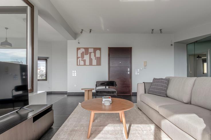 Sala de estar elegantemente projetada com móveis modernos em um apartamento no Pandrosou II em South Athens, Athens