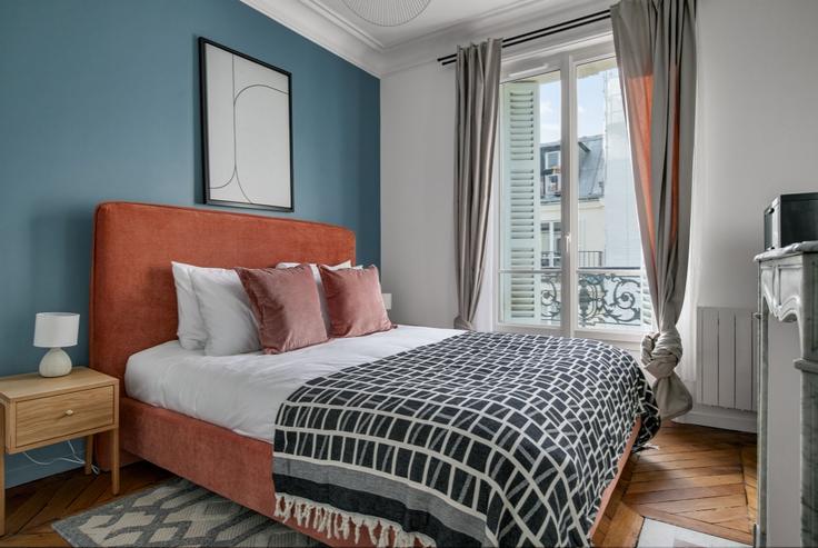 Cozy master bedroom with a large bed, soft lighting, and stylish furniture in a furnished apartment at Maubeuge 82 in 9th arrondissement, Paris
