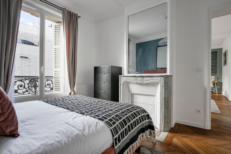 Cozy master bedroom with a large bed, soft lighting, and stylish furniture in a furnished apartment at Maubeuge 82 in 9th arrondissement, Paris