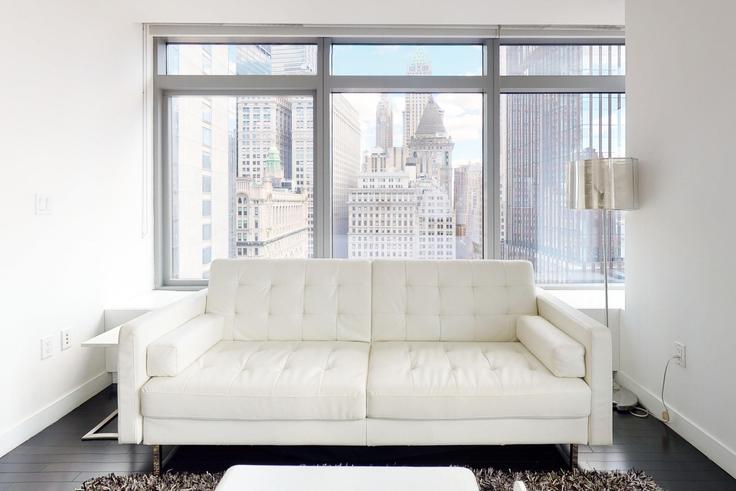 Sala de estar elegantemente projetada com móveis modernos em um apartamento no 123 Washington em Manhattan, New York Sala de estar elegantemente projetada com móveis modernos em um apartamento no 123 Washington em Manhattan, New York