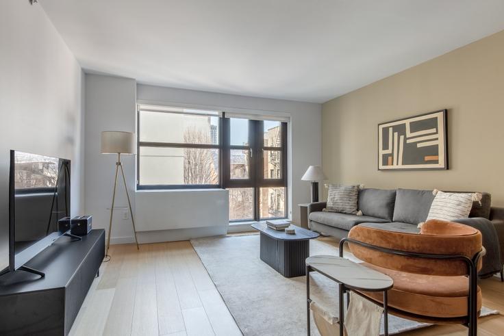 Sala de estar elegantemente projetada com móveis modernos em um apartamento no Sioné em Manhattan, New York Sala de estar elegantemente projetada com móveis modernos em um apartamento no Sioné em Manhattan, New York