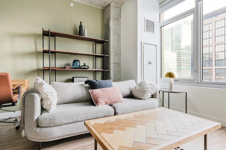 Sala de estar elegantemente projetada com móveis modernos em um apartamento no Emme em Chicago, Chicago Sala de estar elegantemente projetada com móveis modernos em um apartamento no Emme em Chicago, Chicago