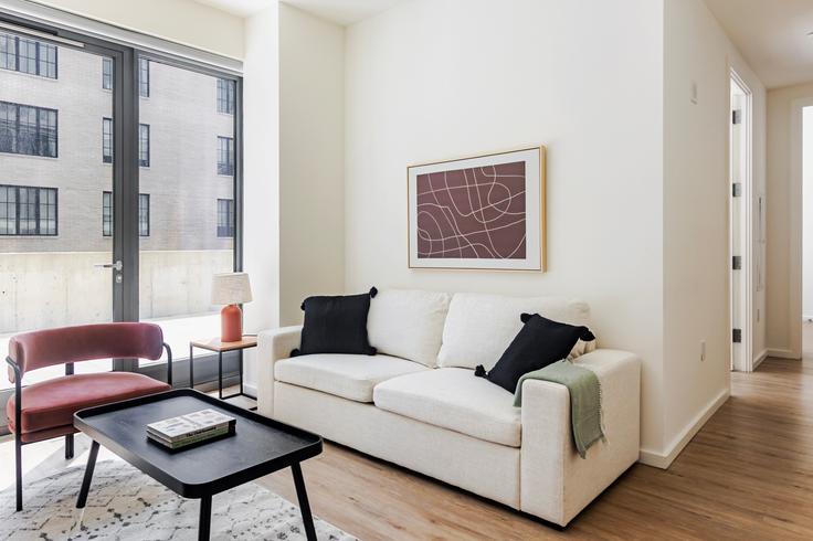 Sala de estar elegantemente projetada com móveis modernos em um apartamento no The Axel em Brooklyn, New York Sala de estar elegantemente projetada com móveis modernos em um apartamento no The Axel em Brooklyn, New York